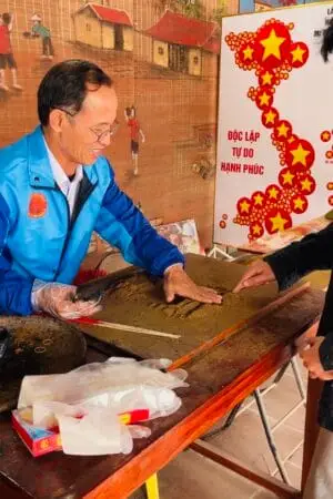 The artisan is instructing tourists on how to make a handmade incense stick at the traditional incense-making village of Quang Phu Cau.