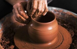 Hands of a local artisan skillfully shaping a clay pot on a traditional potter's wheel in Bat Trang ceramic village.