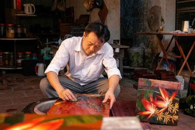 Local artisans at Ha Thai lacquer craft village creating traditional Vietnamese paintings.