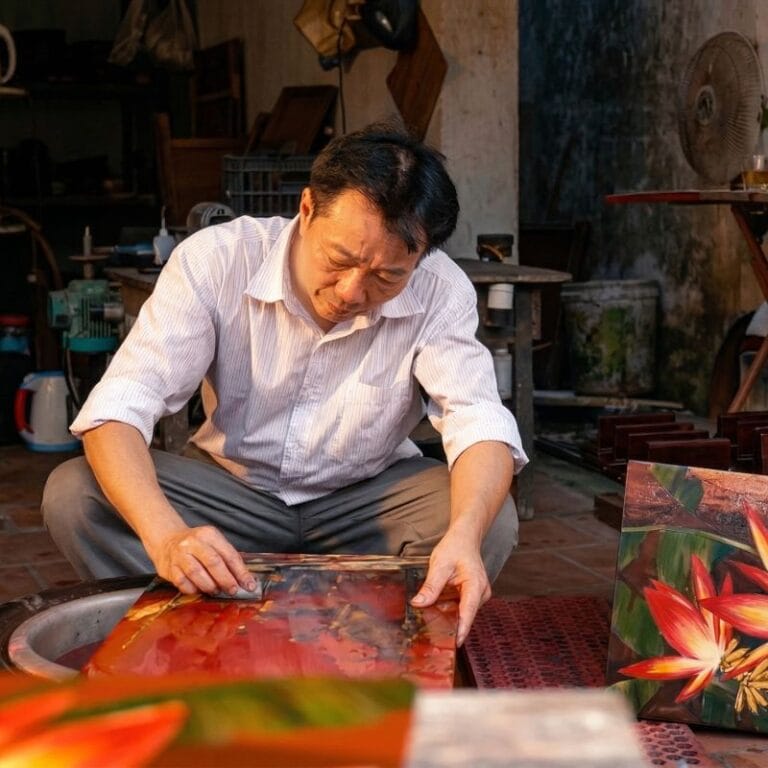 Local artisans at Ha Thai lacquer craft village creating traditional Vietnamese paintings.