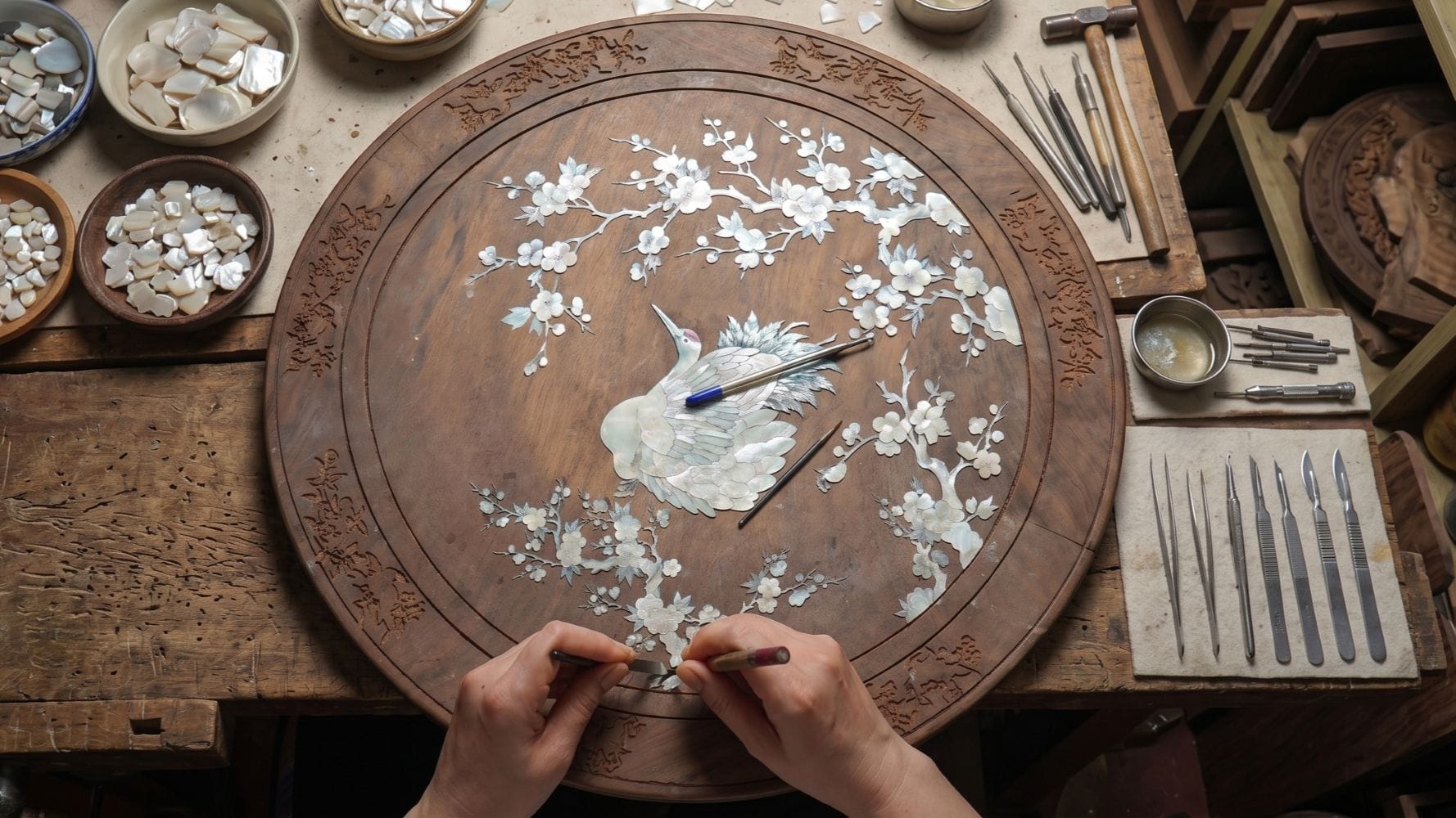 Mother-of-Pearl Inlay Village Tour: The artisan's hands are meticulously inlaying small pieces of mother-of-pearl onto the wooden base to create a work of art.