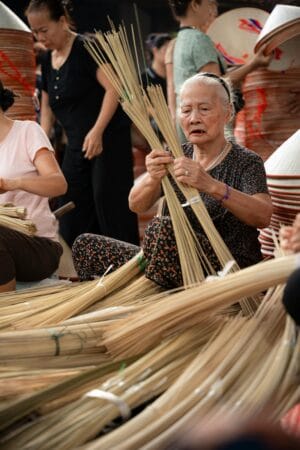 The villagers are selecting small bamboo sticks to make frames for the conical hats.